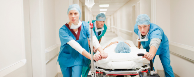 Doctors pushing patient on gurney down hospital corridor